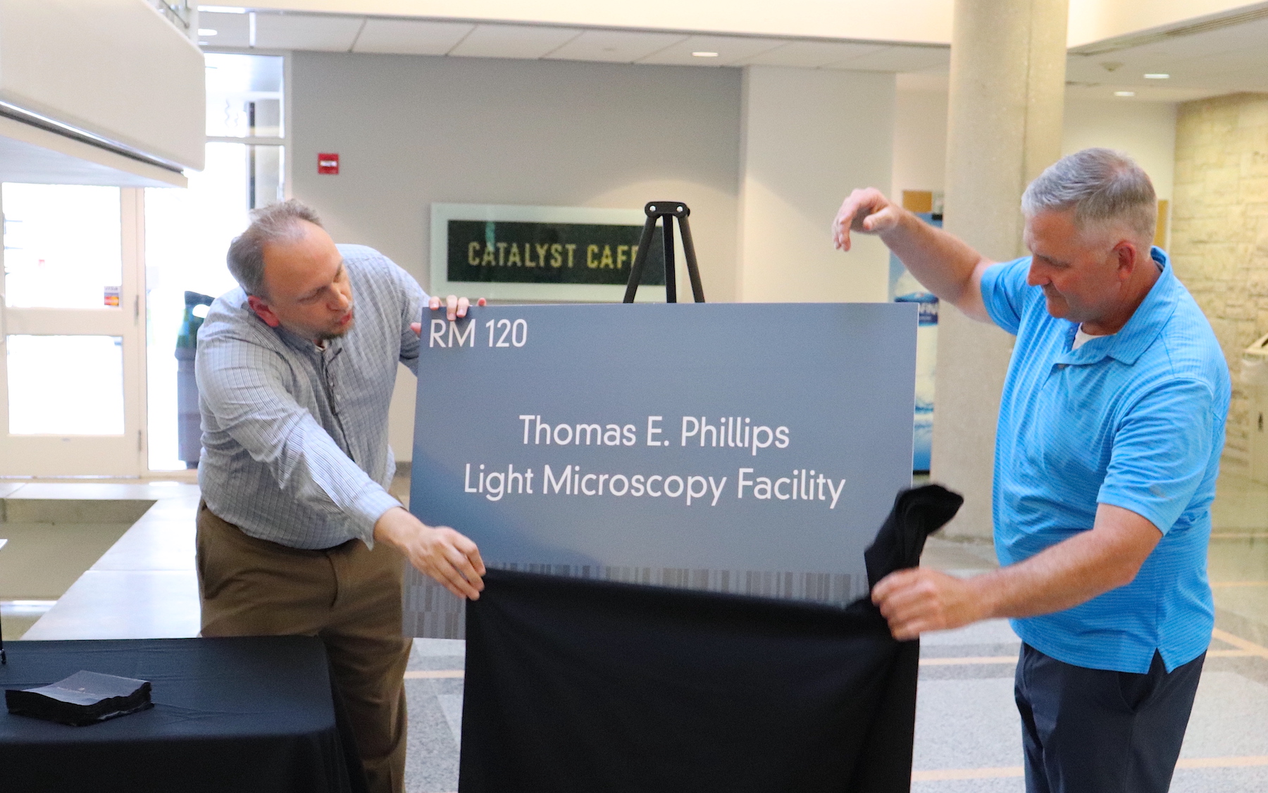 The Thomas E. Phillips Light Microscopy Facility sign is unveiled.
