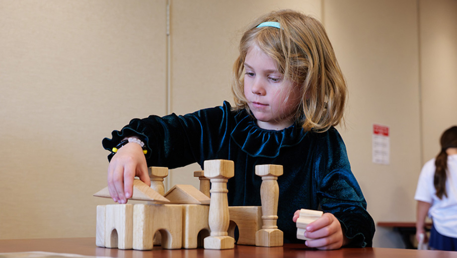 Little girl creates a building with blocks.
