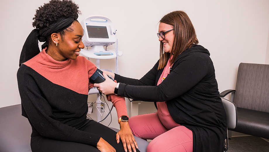 Two women demonstrate a blood pressure cuff in the CTSU.