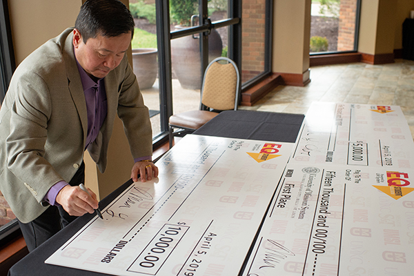 Mun Choi signs large checks