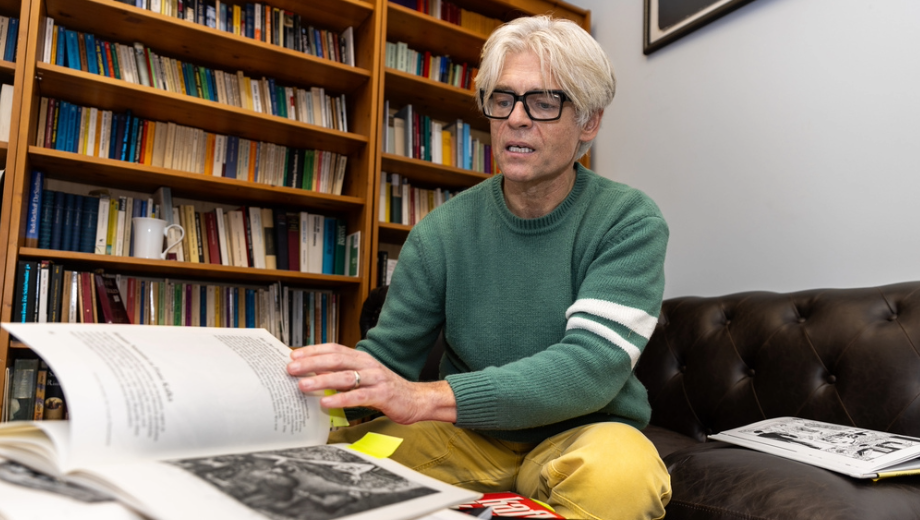 Carsten Strathausen flips through a Kafka book in his office