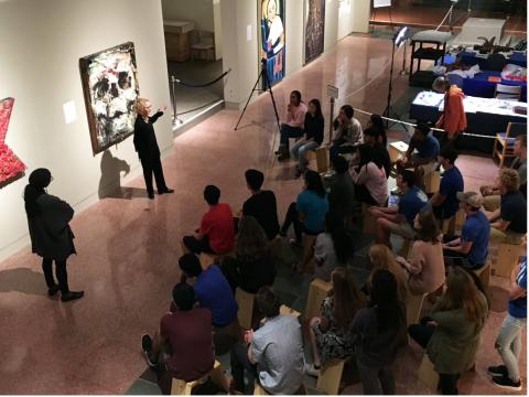 Dr. Fleck explains art pieces to audience in gallery.