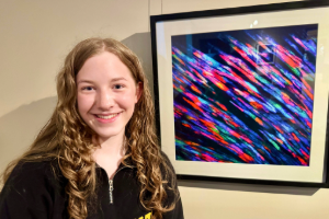 Ava Fleury stands in front of her art that was auctioned at BioNexusKC.