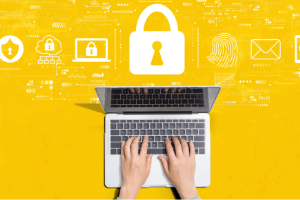 Hands from above typing on a laptop with security icons above it on a yellow background.